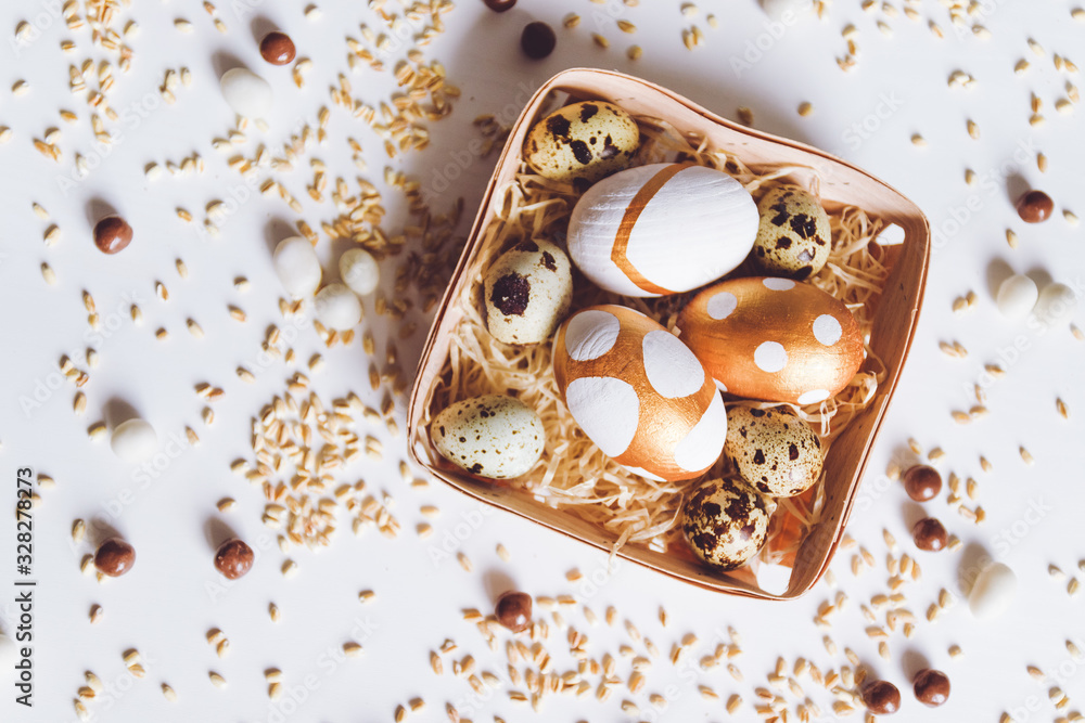 Assorted gold Easter eggs, chocolate dragee candies and millet in a basket on a white background Assorted gold Easter eggs, chocolate dragee candies and millet in a basket on a white background