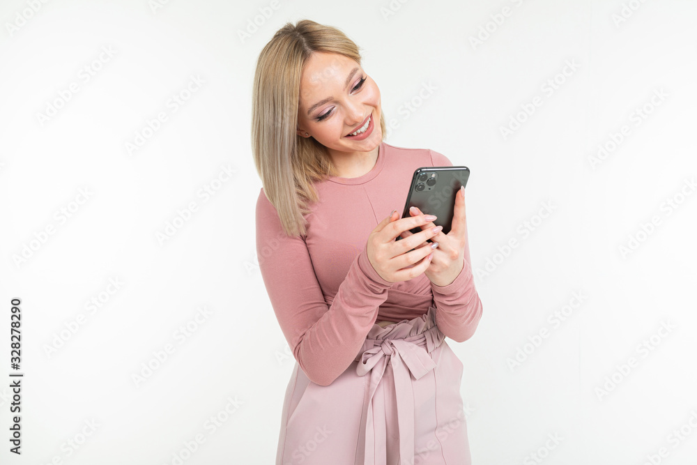 cute blond girl with a phone in her hands on a white background with copy space cute blond girl with a phone in her hands on a white background with copy space