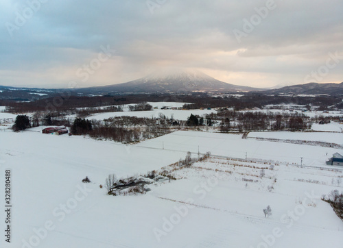 Winter landscape photo of snow covered farm fields and bare trees with the majestic Mount Yotei in the background photo