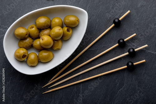 Bowl with anchovy stuffed olives. On black slate. Blackboard. Toothpick. Top View.
