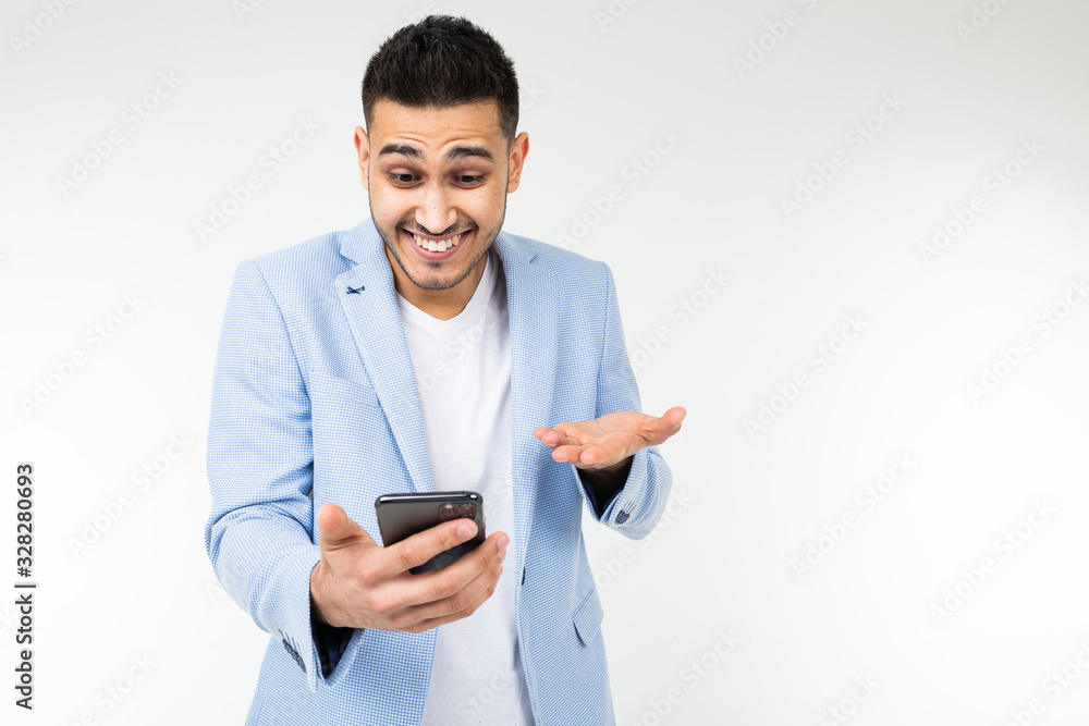 businessman twists at his temple and is surprised with information on the Internet holding a phone in red on a white background studio with copy space businessman twists at his temple and is surprised with information on the Internet holding a phone in red on a white background studio with copy space
