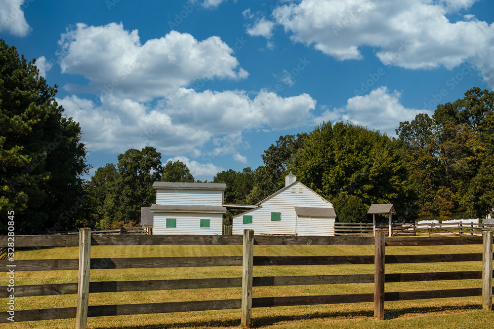 Yellow farm buildings with green shutters beyond wood rail fence Yellow farm buildings with green shutters beyond wood rail fence