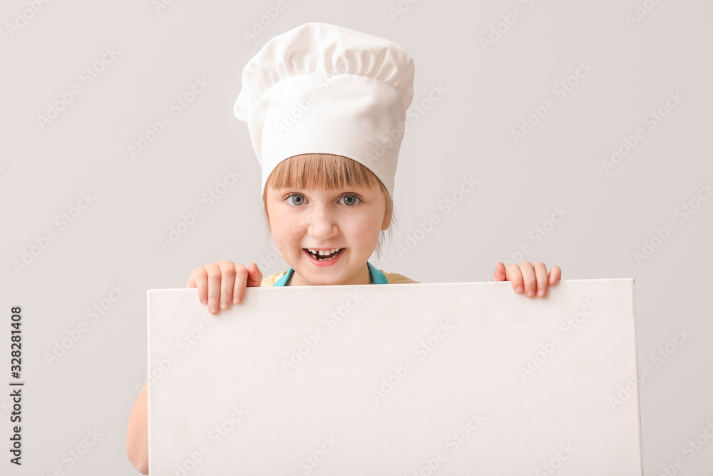 Cute little chef with blank poster on light background Cute little chef with blank poster on light background