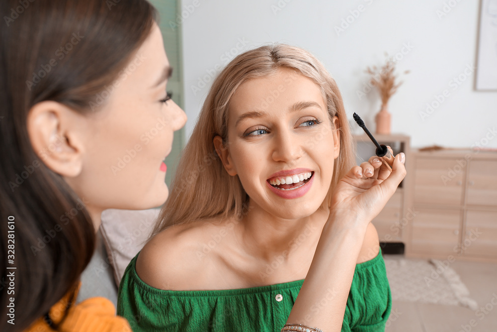Beautiful young women applying makeup together at home Beautiful young women applying makeup together at home