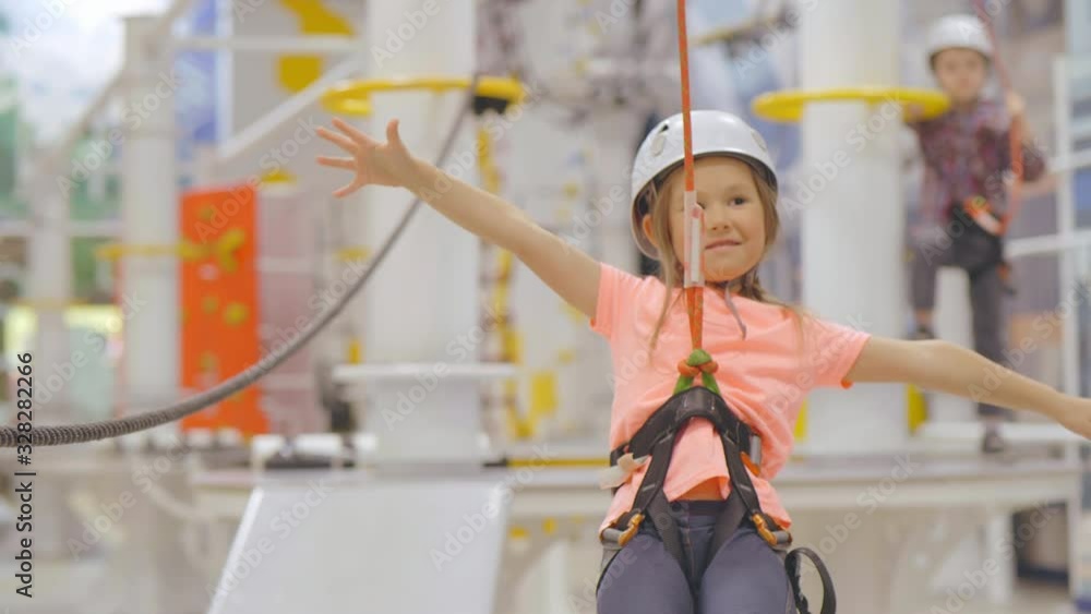 Little girl passing zip line in indoor climbing adventure park