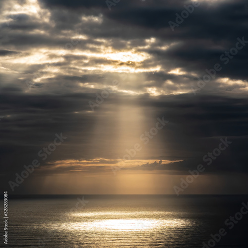 Long aerial view of gray evening clouds over Tasman sea coast at Piha with sun rays