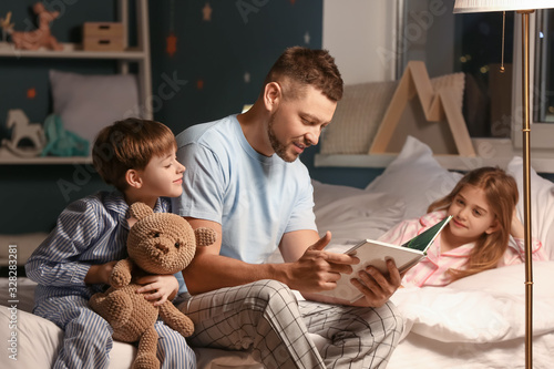 Father and his little children reading bedtime story at home photo