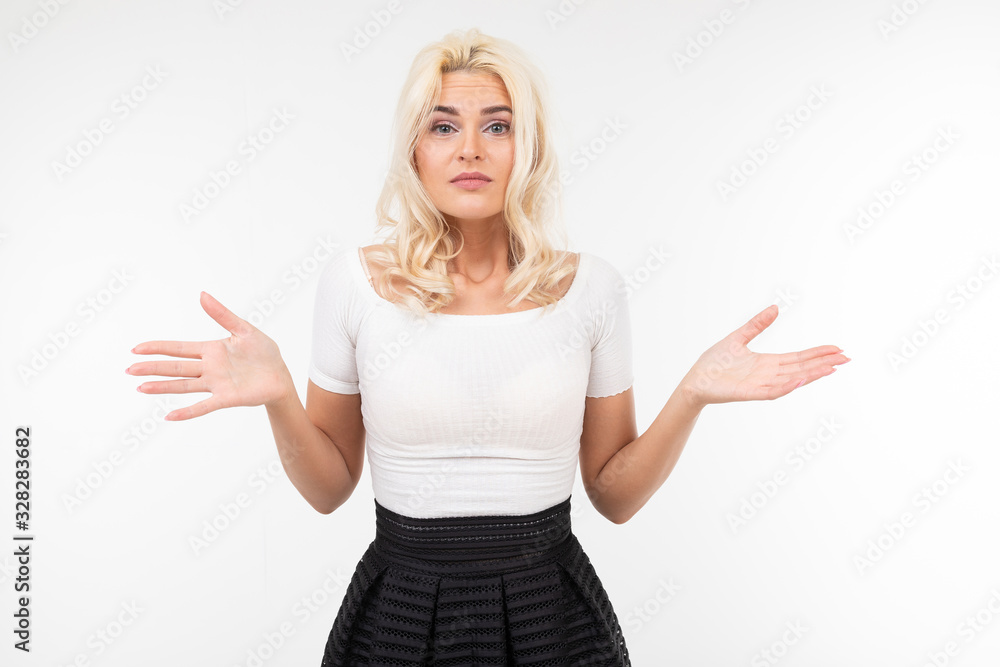 portrait of a surprised blond girl in a white T-shirt waving her arms to the sides on a white background portrait of a surprised blond girl in a white T-shirt waving her arms to the sides on a white background