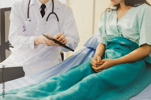 The male doctor gave advice, explained, understood, and diagnosed the disease to a female patient in a patient's bed in the hospital room, and she cooperated for a medical examination.