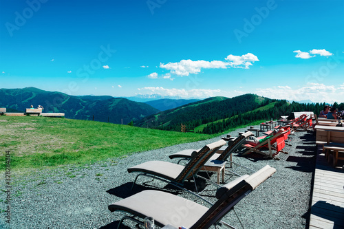 Open air cafe with wooden tables and deck chairs in Alps mountains in Bad Kleinkirchheim Austria photo