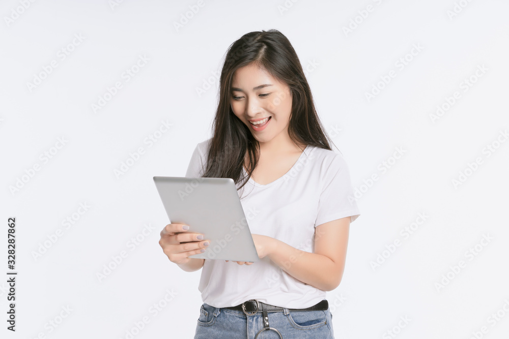 Young beautiful Asian woman in business office standing use tablet in hand, Thai girl enjoy browsing for online shopping store with copy space for advertisement, on isolated white background Young beautiful Asian woman in business office standing use tablet in hand, Thai girl enjoy browsing for online shopping store with copy space for advertisement, on isolated white background