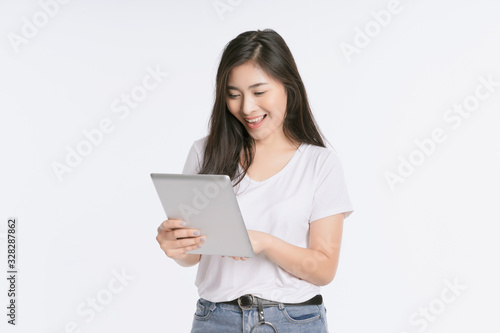 Young beautiful Asian woman in business office standing use tablet in hand, Thai girl enjoy browsing for online shopping store with copy space for advertisement, on isolated white background