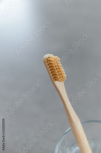 Closeup of a wooden toothbrush. Bamboo biodegradable eco toothbrush against a gray background with copy space. Plastic free concept.