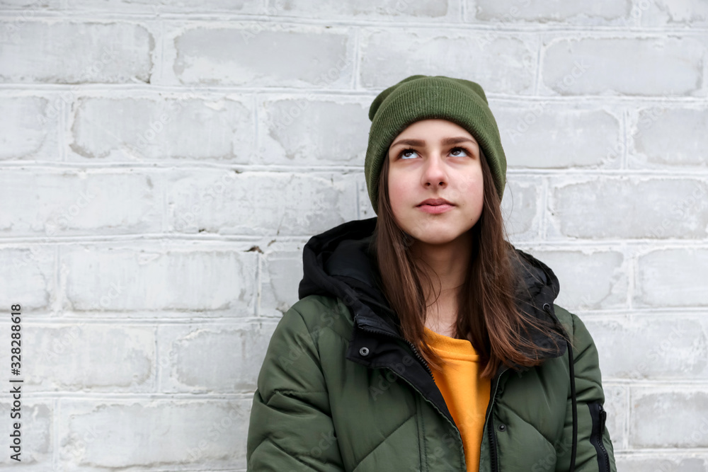 Portrait of a beautiful pensive girl in a yellow sweater and khaki hat, which stands near a white brick wall. The concept of emotions and copy space Portrait of a beautiful pensive girl in a yellow sweater and khaki hat, which stands near a white brick wall. The concept of emotions and copy space