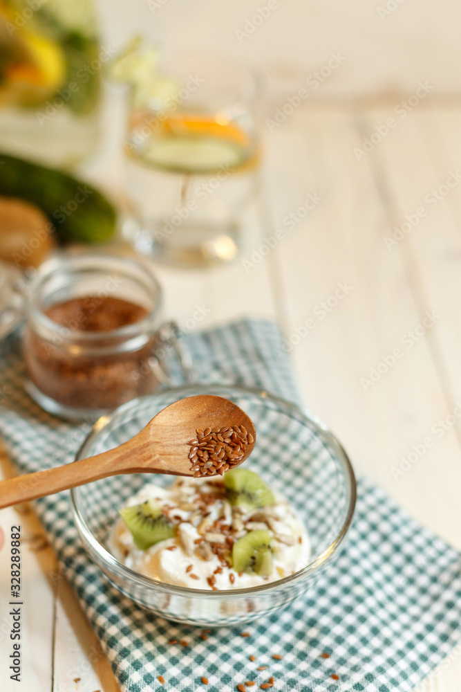 Wooden spoon with flax seeds over soy yogurt with seeds and fruit slices, blurred Wooden spoon with flax seeds over soy yogurt with seeds and fruit slices, blurred