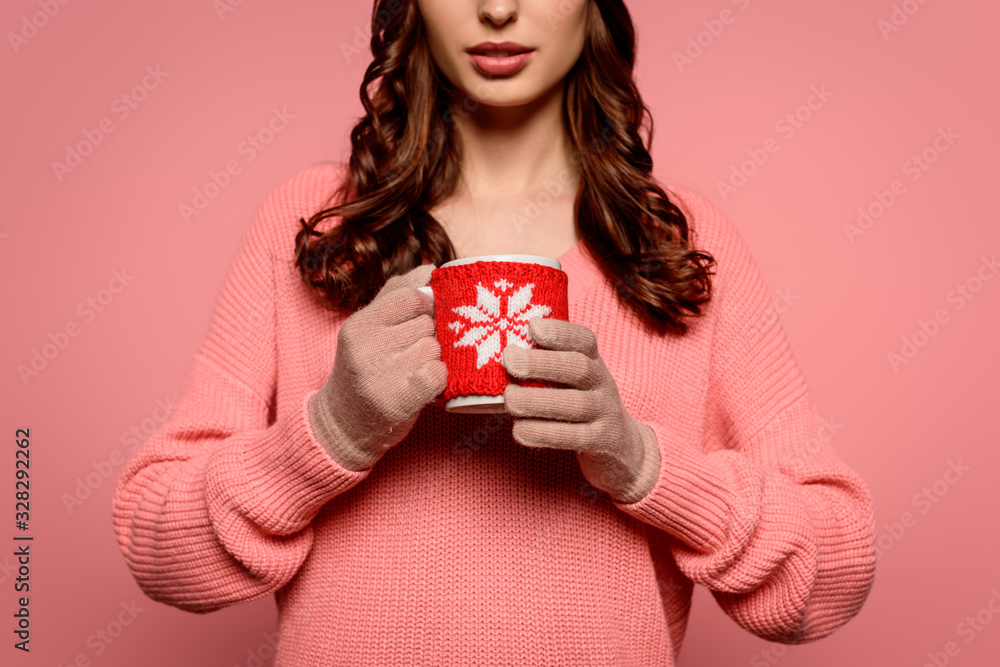 cropped view of young woman in gloves holding mug of warming drink isolated on pink cropped view of young woman in gloves holding mug of warming drink isolated on pink