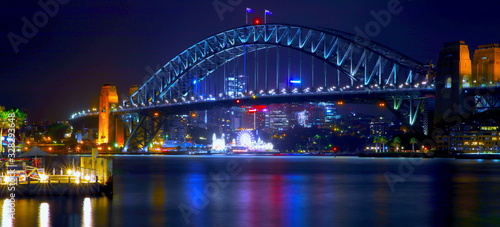 Sydney Harbour Bridge illuminating the harbour and circular quay with vibrant colourful lights at midnight in NSW Australia