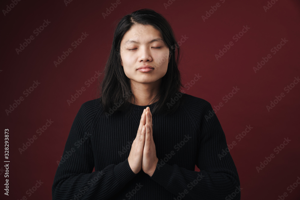 Image of calm asian man posing on camera with palms together Image of calm asian man posing on camera with palms together