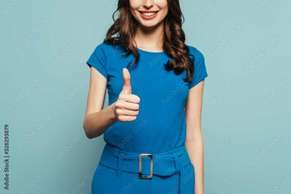 cropped view of smiling girl showing thumb up isolated on blue cropped view of smiling girl showing thumb up isolated on blue