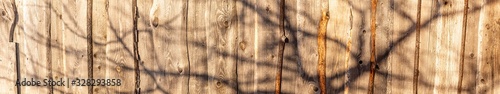 Panoramic fragment of an old wooden fence with a shadow from a tree photo