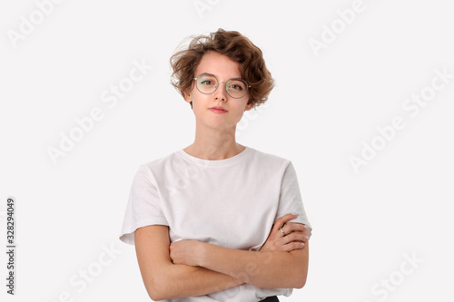 Confident young woamn in a white shirt and eyeglasses looking at the camera holding hands crossed