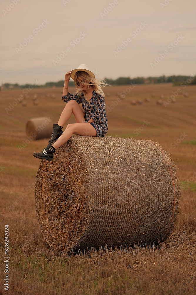 Young girl has a rest in the summer and walks across the field in a hat and dress Young girl has a rest in the summer and walks across the field in a hat and dress