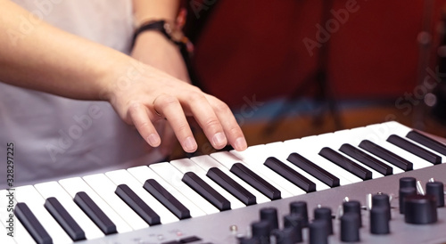 Electronic synthesizer and part of a woman's hand in close-up.