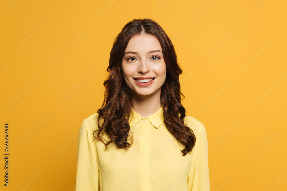cheerful girl with long curly hair smiling at camera isolated on yellow cheerful girl with long curly hair smiling at camera isolated on yellow