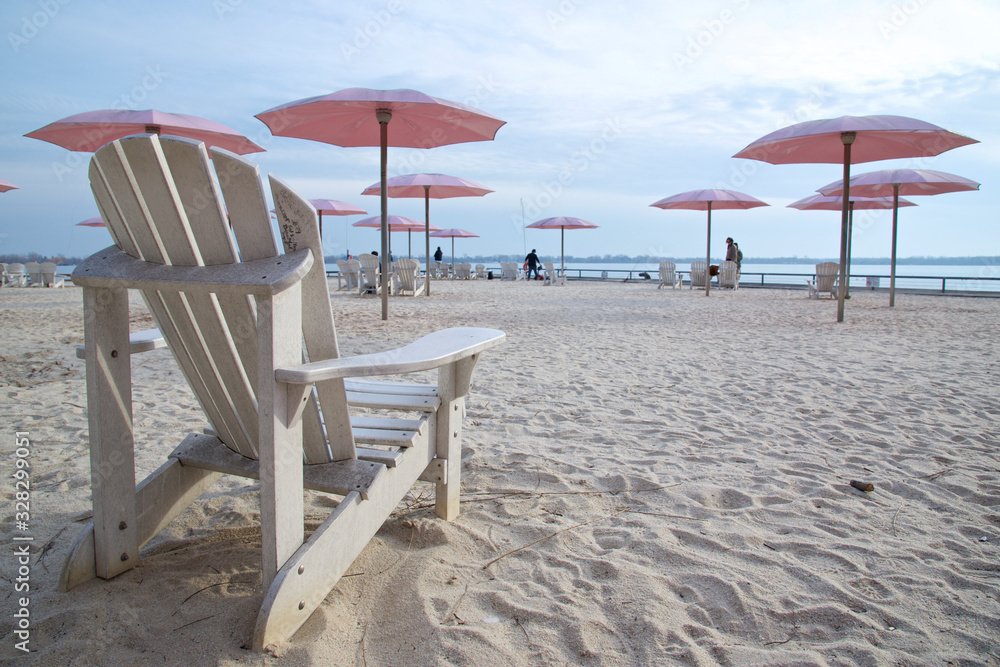 Toronto, Ontario / Canada - Feb 24, 2020 : Beach chairs with umbrella in sandy beach in Lake Ontario