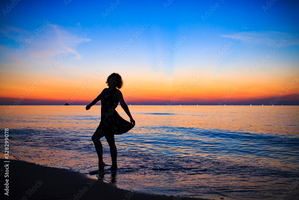夕暮れの海辺で踊る白人女性