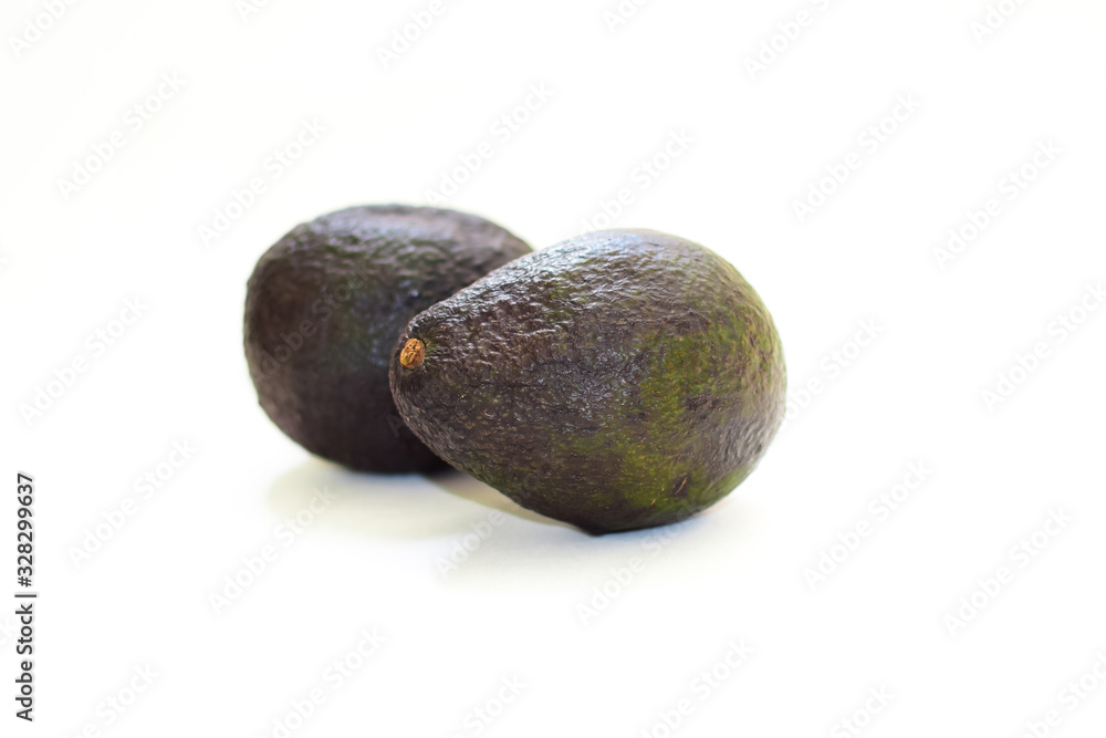 Two avocado fruits on a white isolated background. Two avocado fruits on a white isolated background.