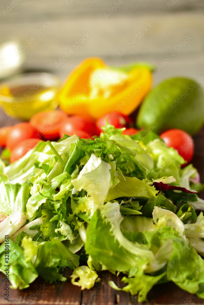 Ingredients for vegan spring and summer salad. Vegetables on a cutting board. Tomatoes, sweet yellow pepper, lettuce, dressing, avocado, oil in a bowl. Ingredients for vegan spring and summer salad. Vegetables on a cutting board. Tomatoes, sweet yellow pepper, lettuce, dressing, avocado, oil in a bowl.