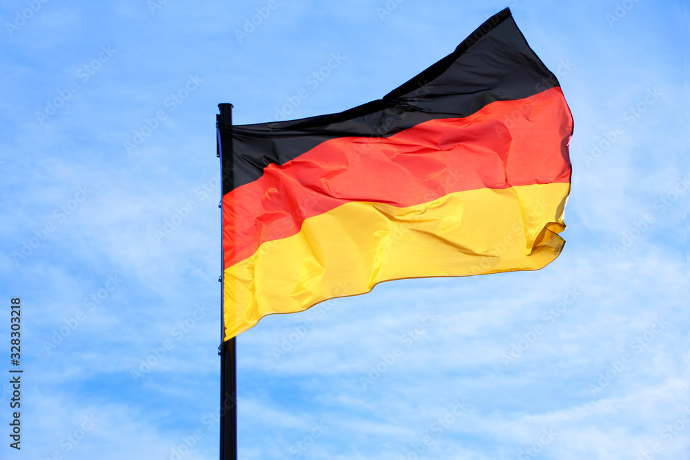silk national flag of the state of Germany against the blue sky, the concept of tourism, economy, politics, emigration, global business silk national flag of the state of Germany against the blue sky, the concept of tourism, economy, politics, emigration, global business