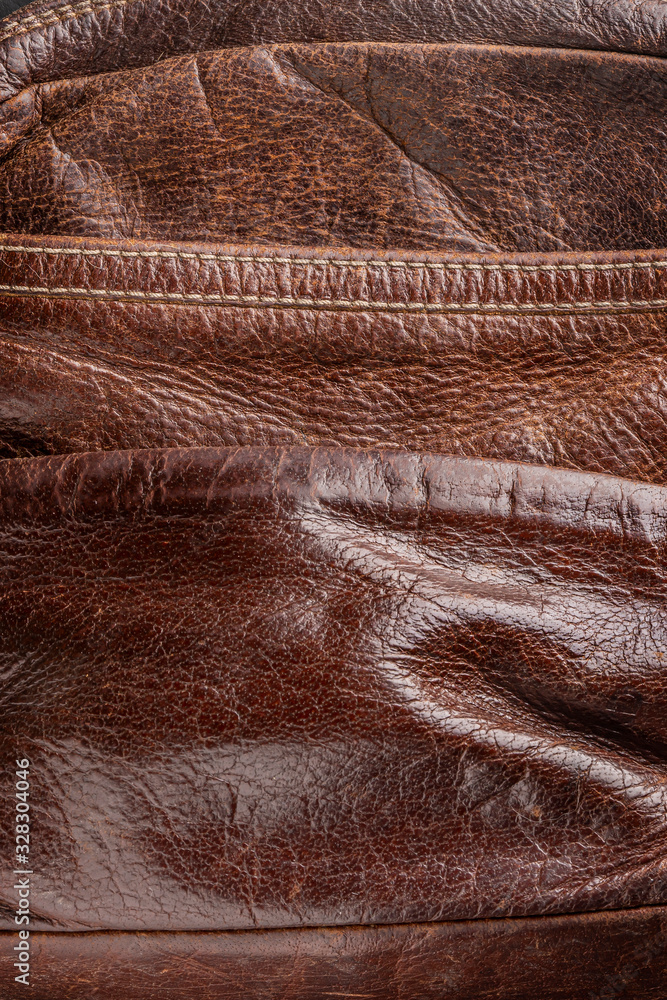 background-brown old leather, a fragment of a shabby bag, a stylish thing close-up, vertical photo. background-brown old leather, a fragment of a shabby bag, a stylish thing close-up, vertical photo.