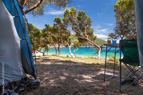 Camping on the sea, tent and camping table under olive trees. Lichnos beach, Epirus, Greece.