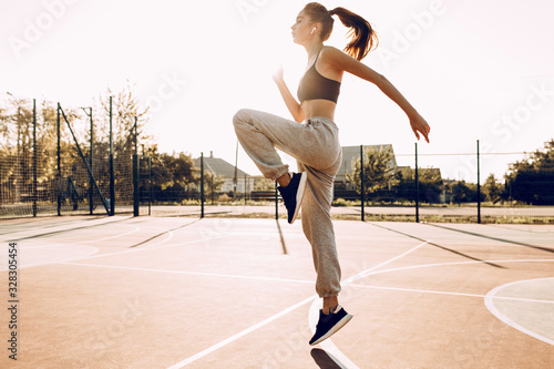 Attractive young girl sportswoman training outdoors, wearing headphones, doing jumps © Shopping King Louie