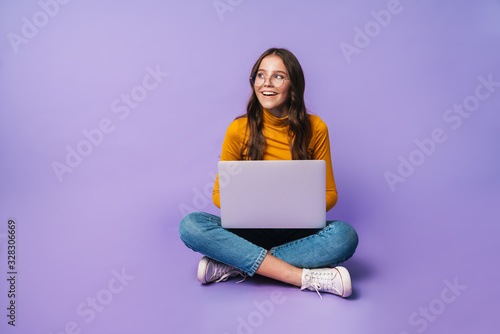 Image of young woman using laptop while sitting with legs crossed