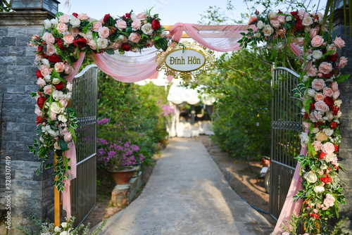Fototapeta Naklejka Na Ścianę i Meble -  BEN TRE PROVINCE, VIETNAM - MARCH, 2020: The engagement gate in western Vietnam is decorated with many pink flowers and chiffon fabric, traditional wedding
