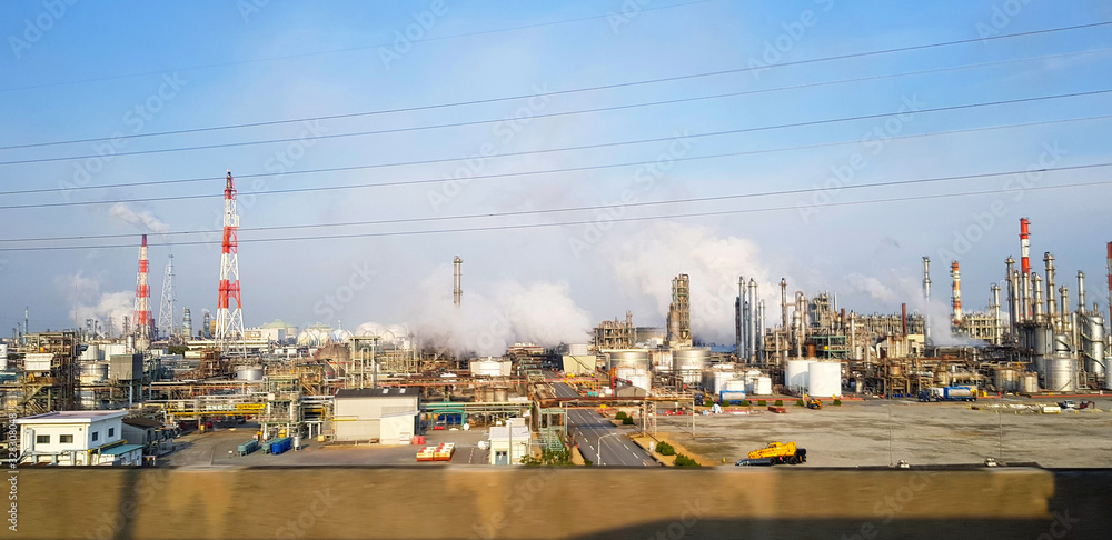 Many factory emits pollutants and smoke into the air and atmosphere with clear blue sky and wire background in Japan. Pollution and Environment concept
