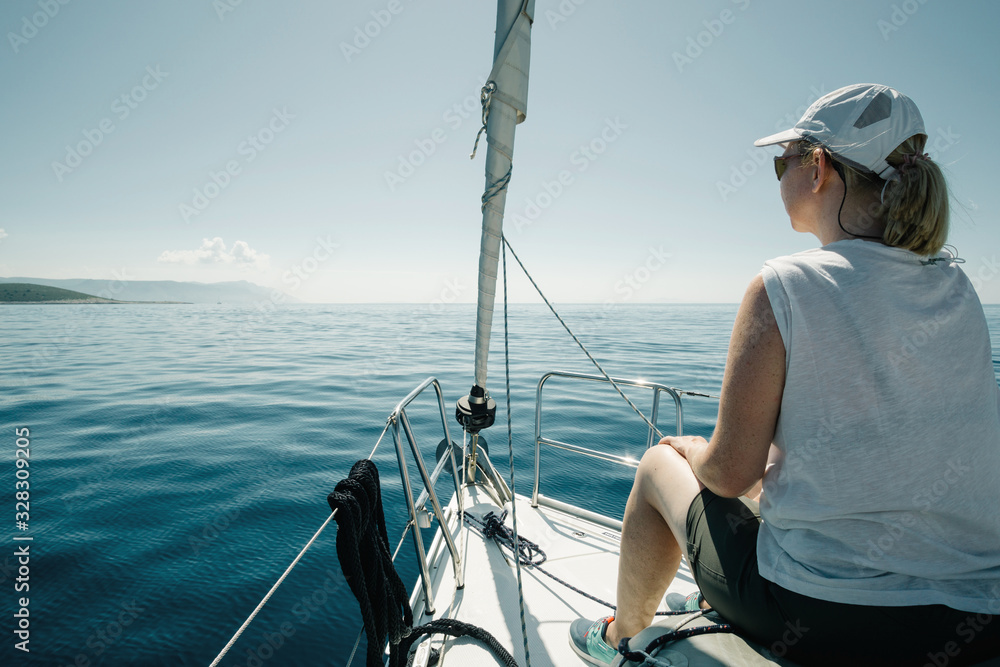 Obraz premium Woman sitting on the ships bow enjoying the yacht trip. Sailing, yachting and travel concept.