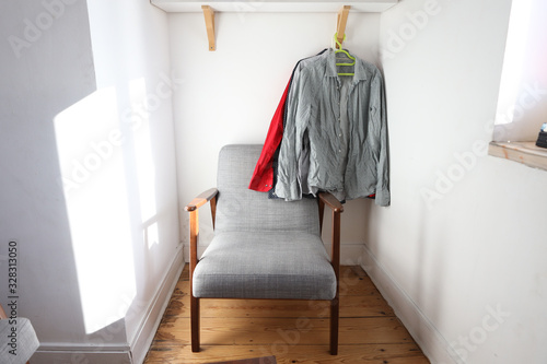 In the sunny room hang men's shirts under a comfortable chair © Kateryna
