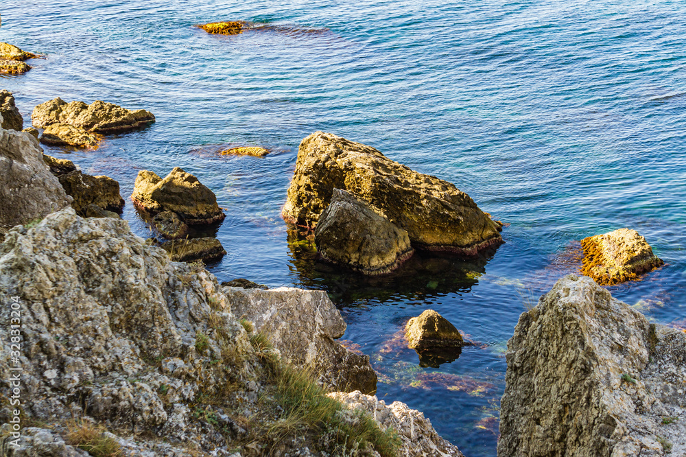 Rocky coast of Black Sea. Cape Alchak. Wildlife near ancient city built by Genoese. Velvet season in Sudak in Crimea. Huge stones and boulders in sea and on background of sea. Close-up.