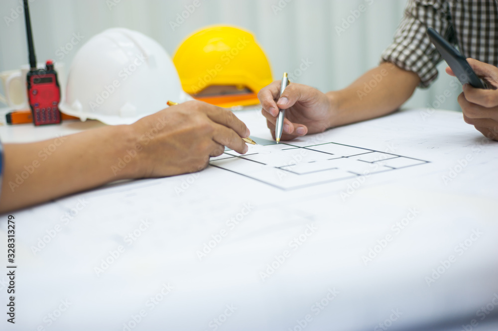 Architects are discussing and planning together at the desk with blueprints. Architects are discussing and planning together at the desk with blueprints.
