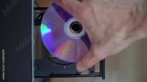 A male programmer inserts a CD-DVD from a computer drive. View from above. Outdated obsolete technology.