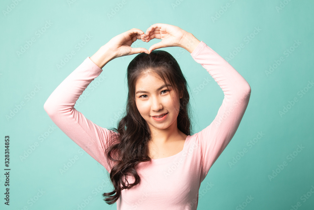 Fototapeta premium Young Asian woman gesturing heart hand sign.