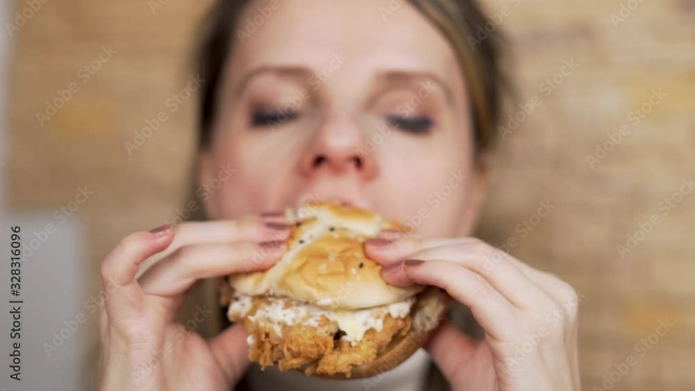 Hungry Woman Appetising Eating a Chicken Burger Close- up. Focus on the Burger Hungry Woman Appetising Eating a Chicken Burger Close- up. Focus on the Burger
