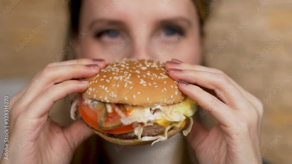 Woman Eating A Burger. Close- up of the Burger. Focus on the Burger. Woman Eating A Burger. Close- up of the Burger. Focus on the Burger.