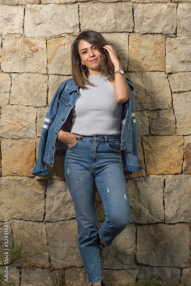 Pretty latin single woman portrait outdoors with a stone wall of background Pretty latin single woman portrait outdoors with a stone wall of background