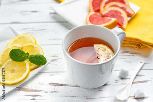 cup of black tea with lemon and grapefruit , close up on the white wooden background