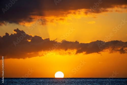 Hawaii Sunset over the Water with Dramatic clouds and sun below horizon